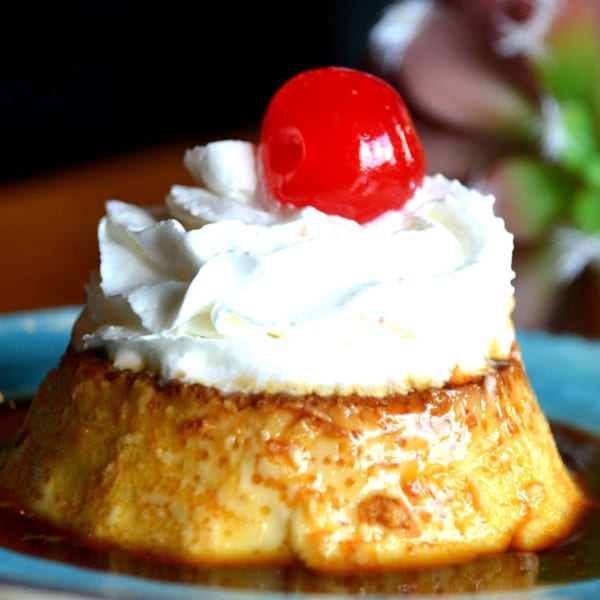 Angelina's Mexican Restaurant's flan dessert, topped with whipped cream and a bright red cherry.