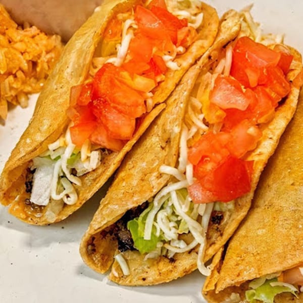 Three crispy Angelina's Mexican Restaurant tacos filled with meat, lettuce, cheese, and diced tomatoes.
